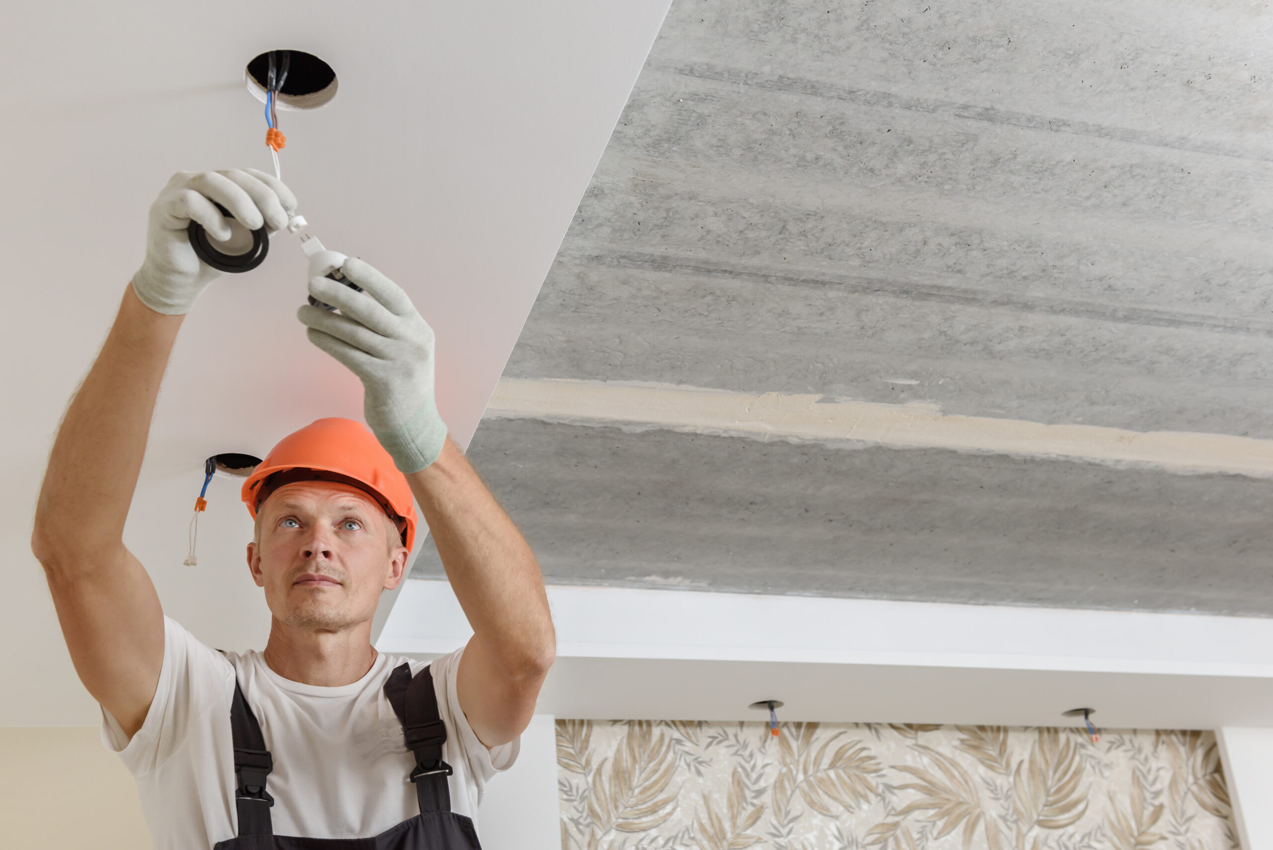 The electrician is installing LED spotlights on the ceiling.